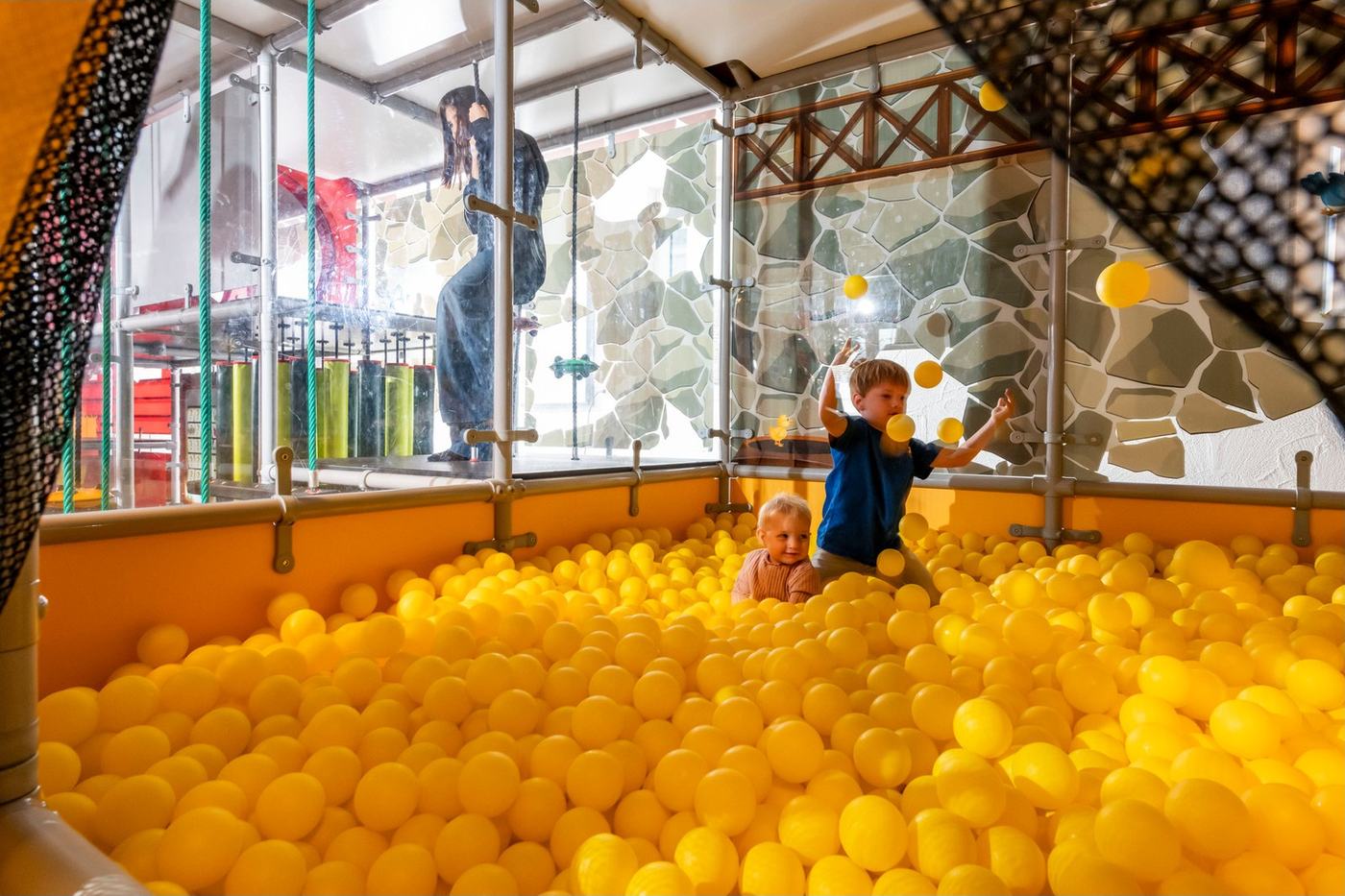 Kind im gelben Bällebad des Indoor-Spielplatzes