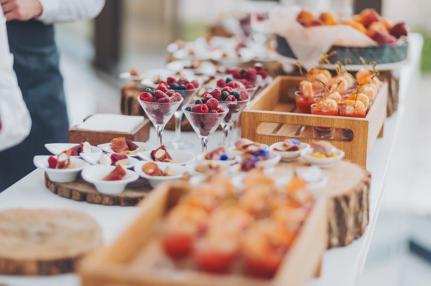 Buffet mit Häppchen, Früchten und Desserts auf Holzbrettern