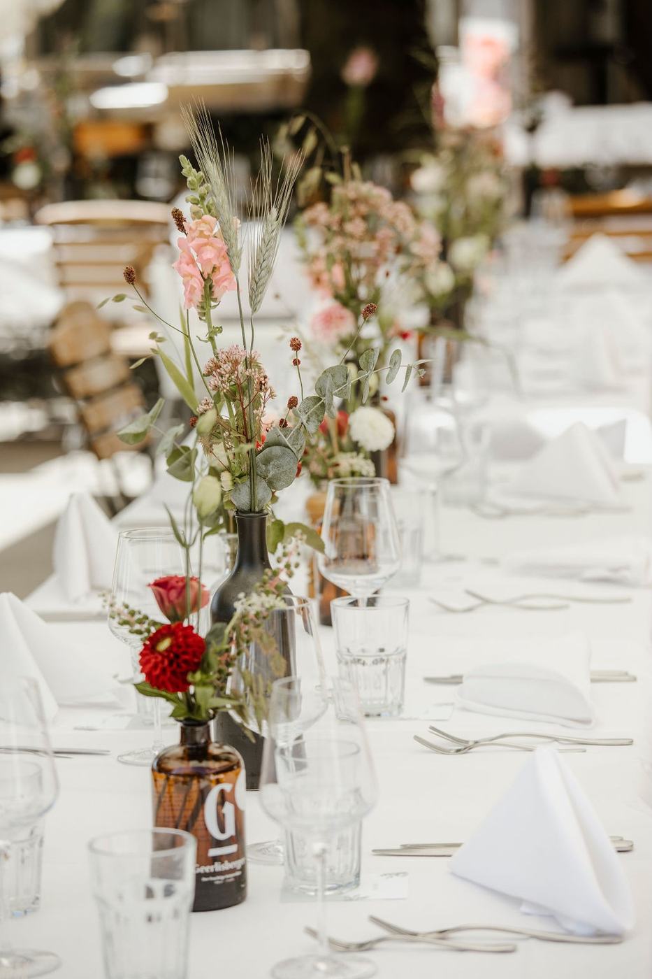 Hochzeitstafel mit Geerlisburger Wasserflasche und roten Dahlien