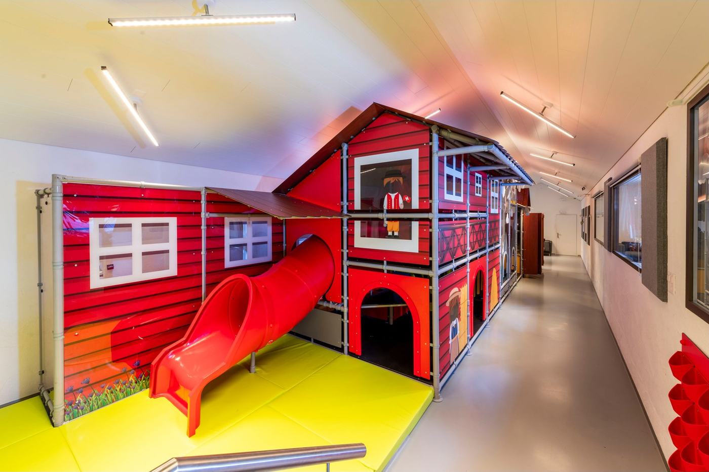 Rotes Spielhaus mit Rutsche im Indoor-Spielplatz